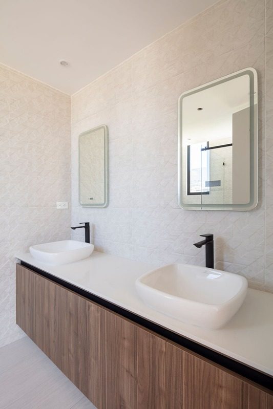 Baño con doble lavabo y mueble de madera de nogal